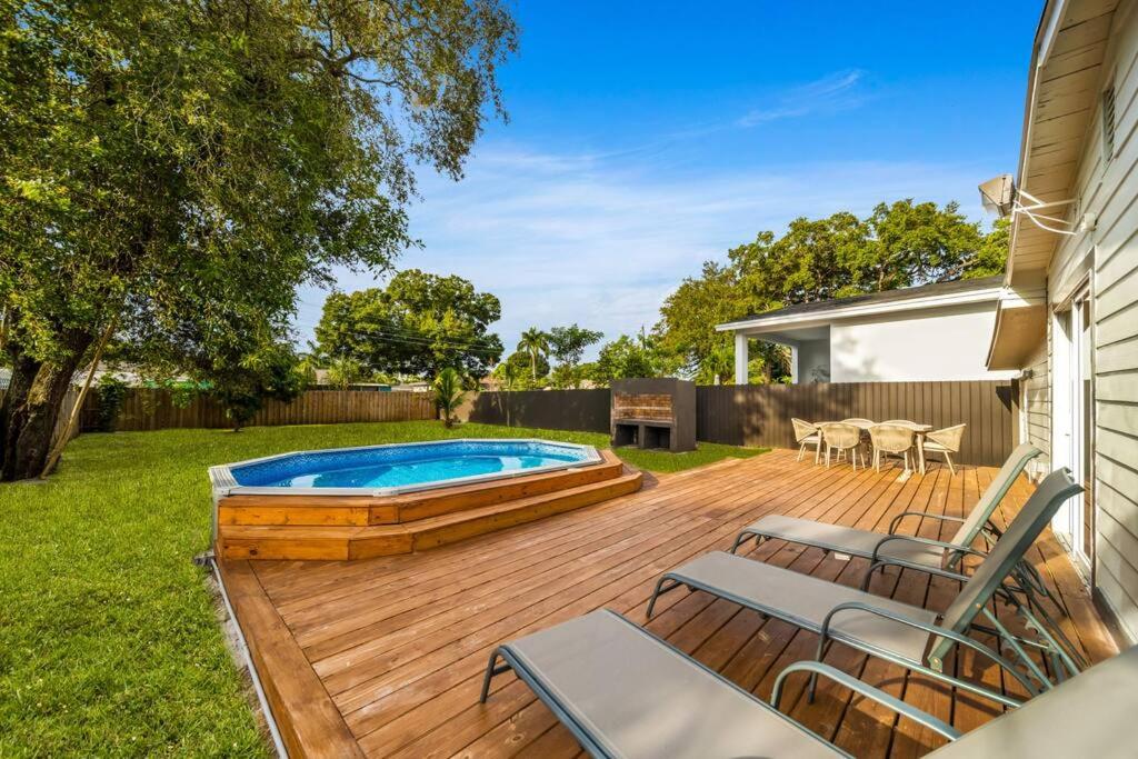 un patio trasero con terraza de madera y piscina en Home In Fort Lauderdale 3 Bedrooms & private pool!, en Fort Lauderdale