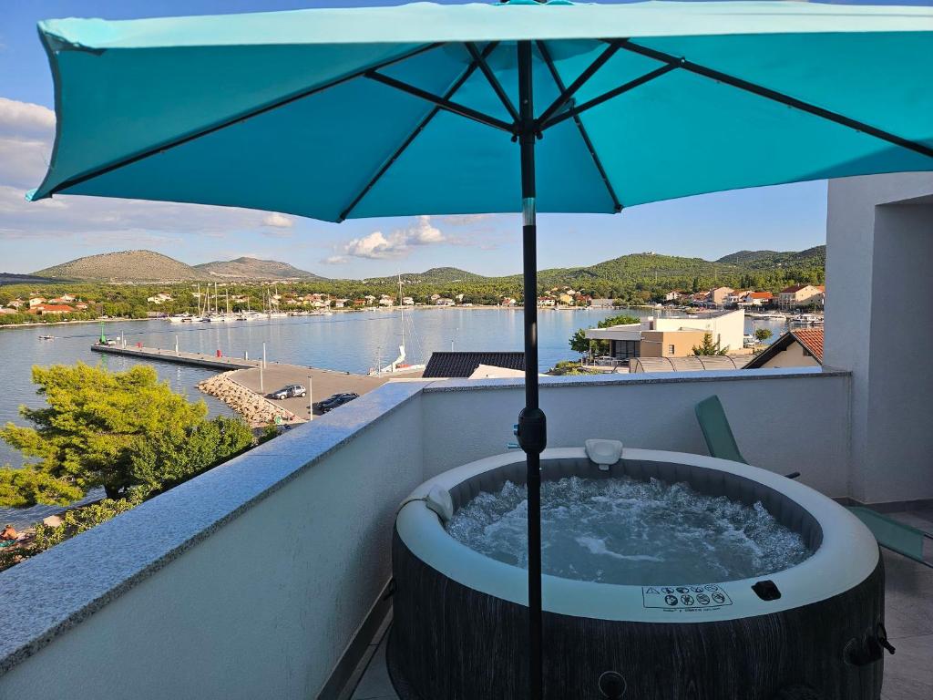 a hot tub on a balcony with an umbrella at Apartments Picikato in Bilice