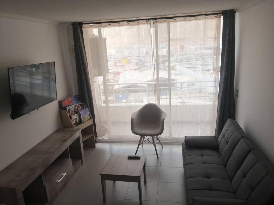 sala de estar con sofá, silla y ventana en Sensacional Departamento cerca Zofri 2 Habitaciones 2 Baños Iquique, en Iquique