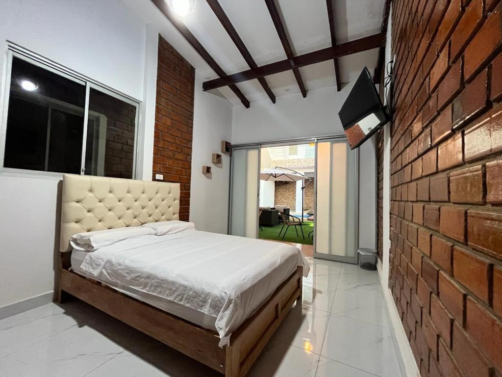 um quarto com uma cama e uma parede de tijolos em La casita de Vale em Tarapoto