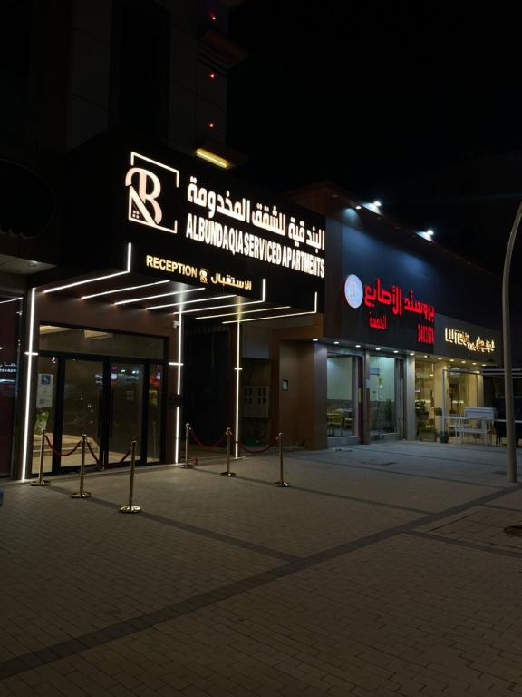 un edificio con un cartel delante de él por la noche en شقق البندقية للوحدات الفندقية ALBUNDUQI HOTEl, en Riad