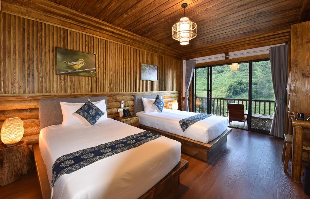 a bedroom with two beds and a large window at Maison de Lao Chai in Sapa