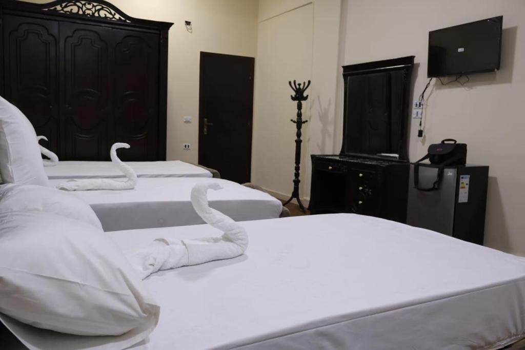 um quarto com 3 camas com lençóis brancos e cisnes em رويال ماجيك no Cairo
