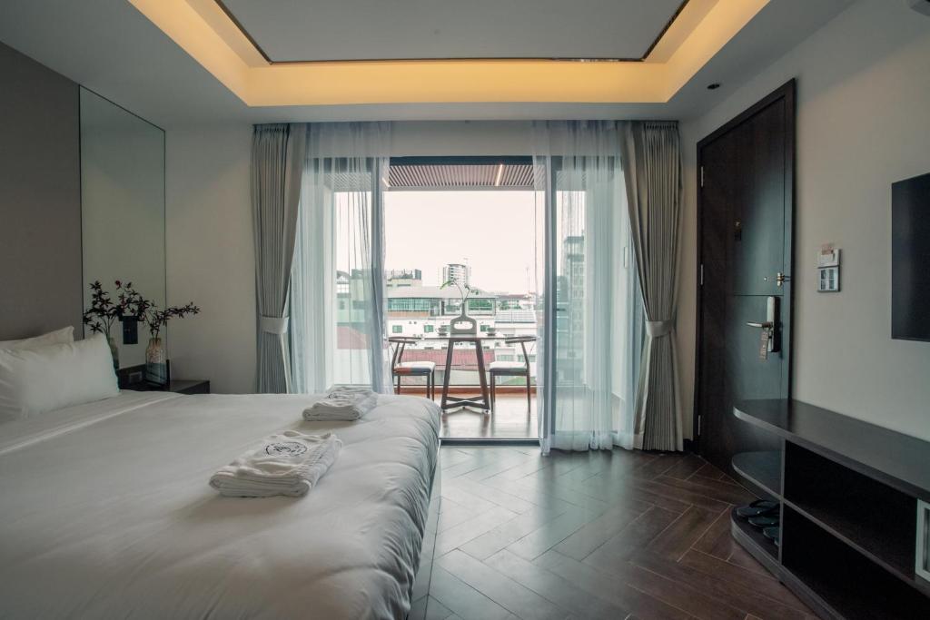 a bedroom with a bed and a balcony with a table at Riverside Hotel in Vientiane