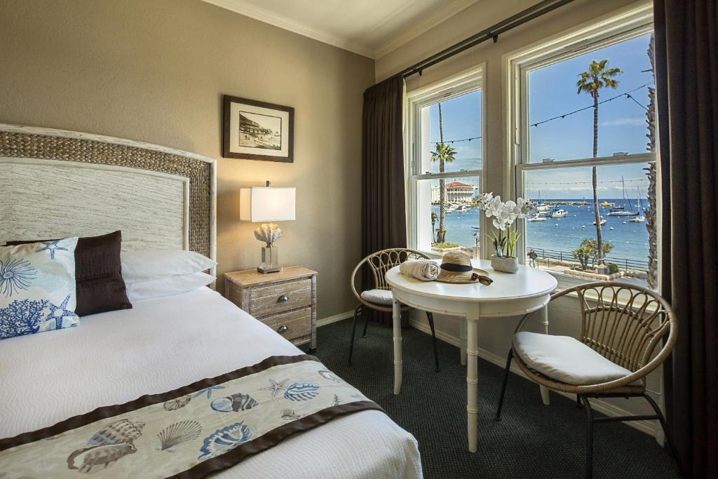 a bedroom with a bed and a table and a window at Hotel Mac Rae in Avalon