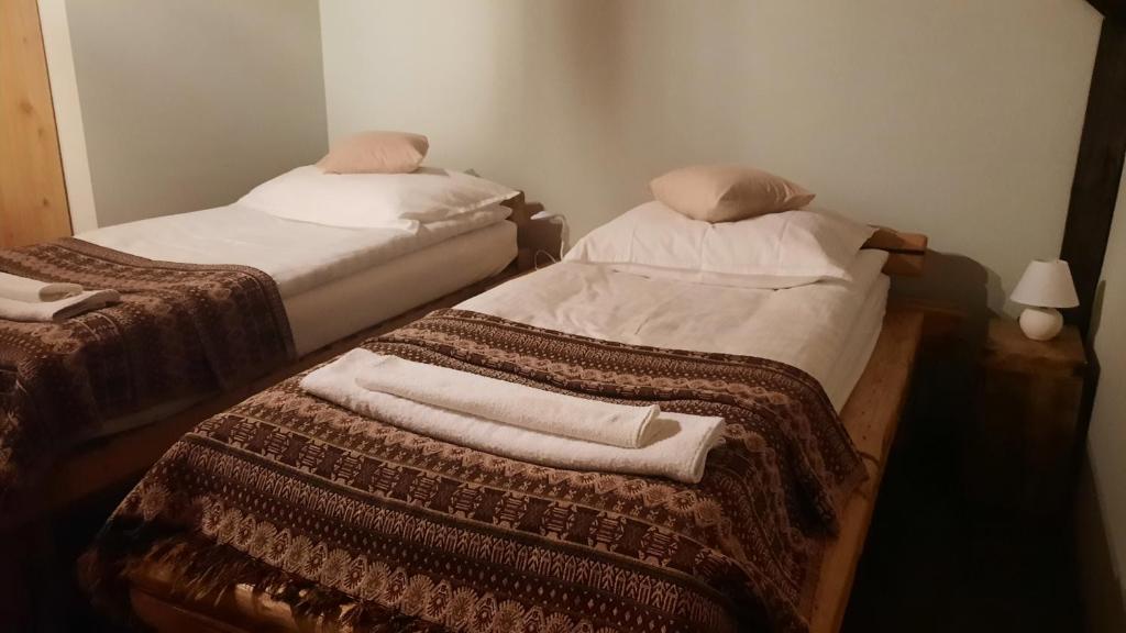 Dos camas en una habitación con toallas. en Kontra szálláshely, en Sándorfalva