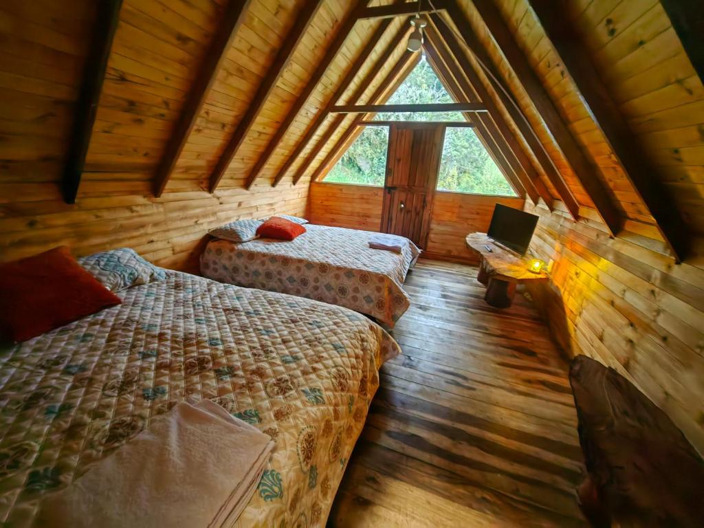 a bedroom with two beds in a wooden cabin at Cabañas del bosque in Choachí