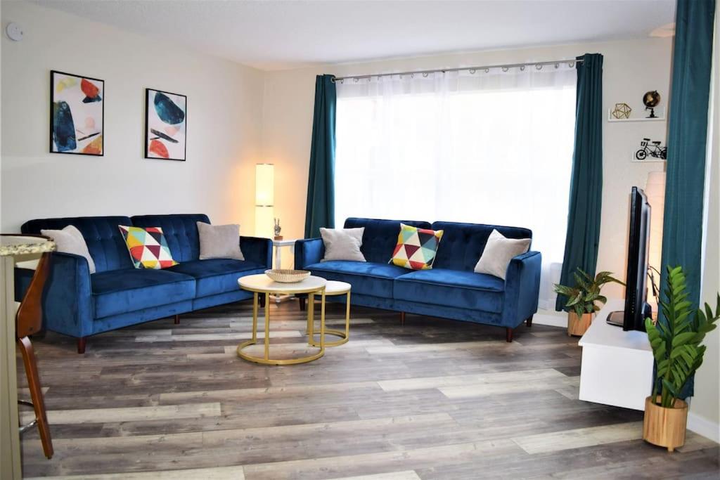 uma sala de estar com dois sofás azuis e uma mesa em 2bd/2bth Modern Condo on International Dr. w Pool ! Near Sea World and Universal em Orlando