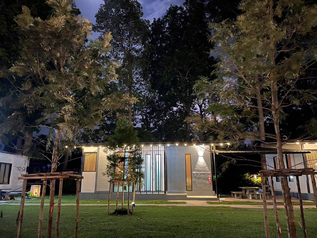 une maison éclairée la nuit avec des arbres dans la cour dans l'établissement Suptara Resort, à Nakhon Nayok