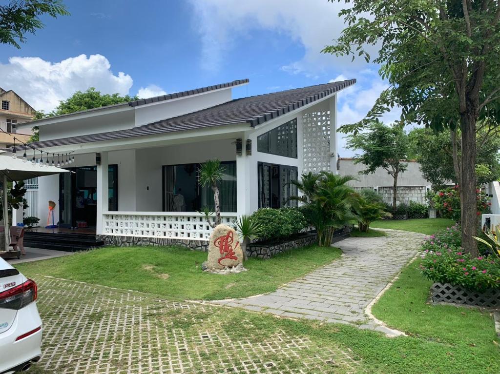 een wit huis met een tuin en een oprit bij Villa Kim Yến Lagi in La Gi