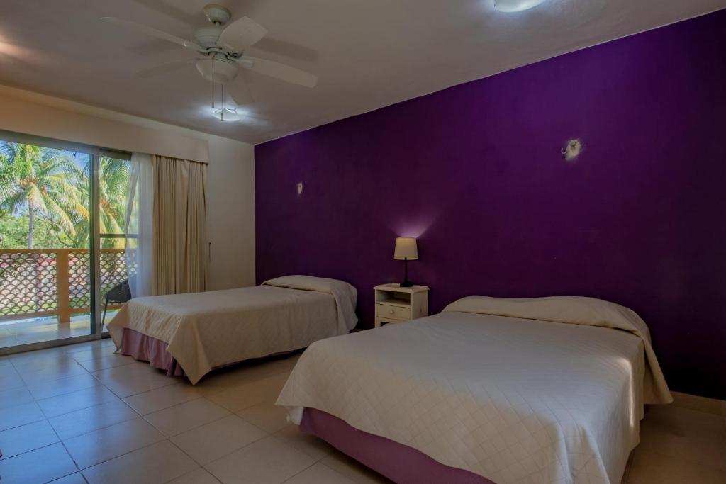 a bedroom with two beds and a purple wall at Marysol d10 private beach next to nomads in Isla Mujeres