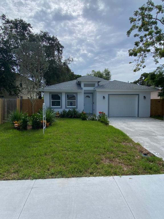 a white house with a garage and a driveway at Mango Tree House in Lake Worth