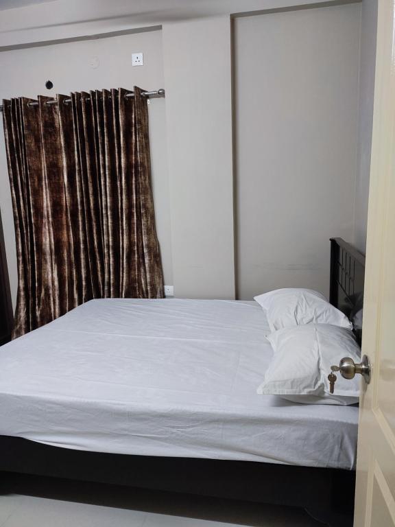 una camera da letto con un letto con lenzuola bianche e una finestra di Rahuls castle a Visakhapatnam