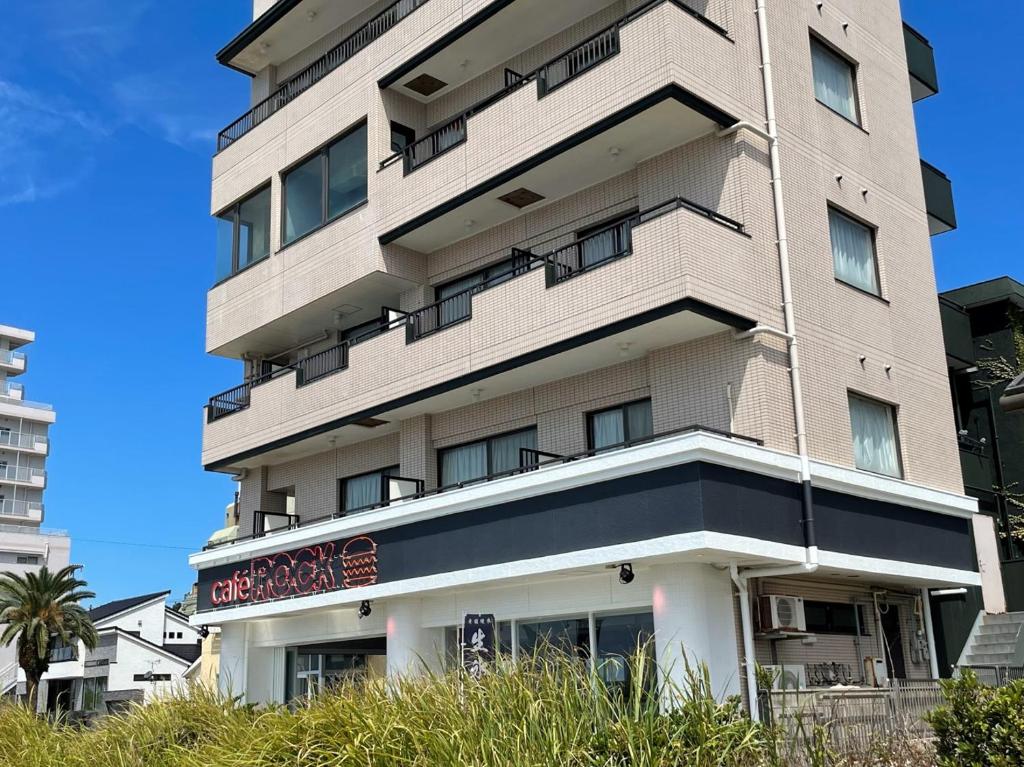 um edifício alto com um sinal em frente em Support Inn Minami-Chita Annex Hamachaya em Minamichita