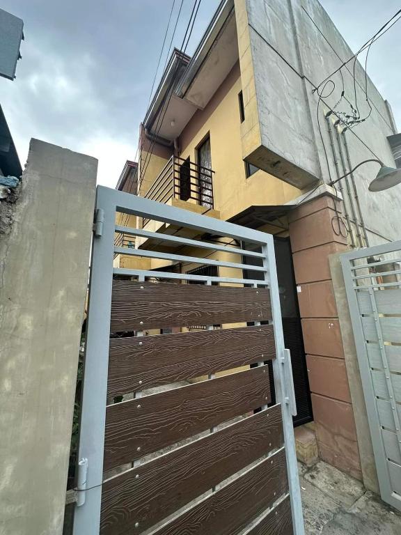 um portão de madeira em frente a uma casa em Aien's Apartelle em Mati