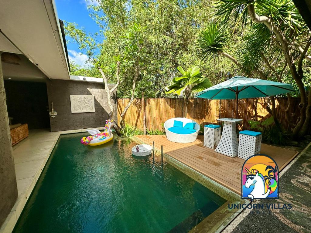 a backyard with a pool with an umbrella and chairs at Villa di Sawah - by Unicorn Villas Bali in Kerobokan