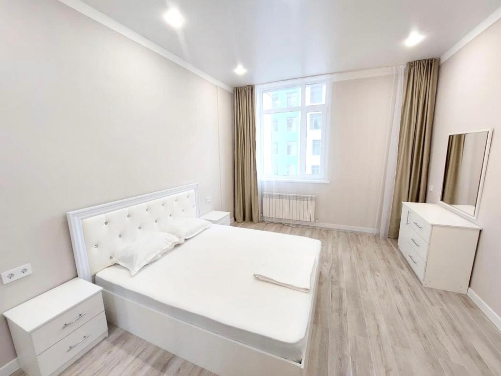 ein weißes Schlafzimmer mit einem großen weißen Bett und einem Fenster in der Unterkunft Уютные апартаменты ЖК Galamat towers in Taldykolʼ