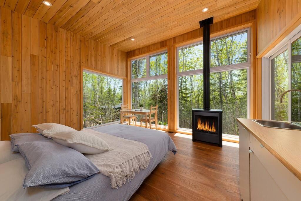 ein Schlafzimmer mit einem Bett und einem Kamin in der Unterkunft Tanières MicroChalets Charlevoix in Baie-Saint-Paul