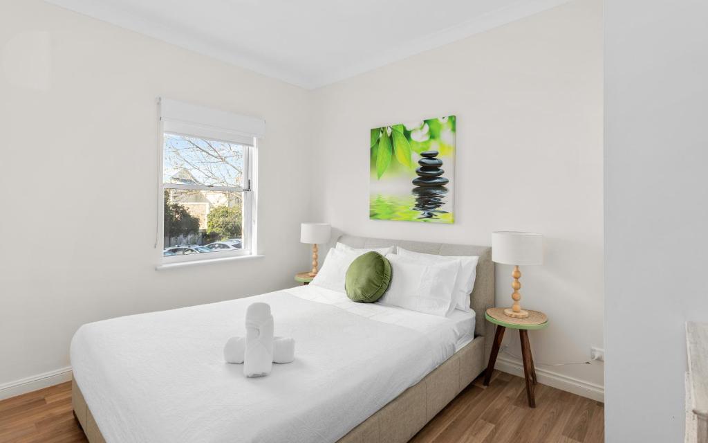 a bedroom with a bed with white sheets and a window at SEA BREEZE @ Smugglers Inn in Victor Harbor