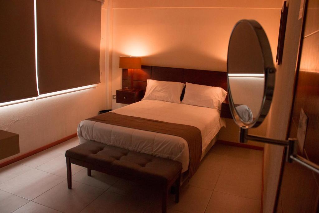 Dormitorio con cama con espejo y taburete en Hotel Tlaxcala en Tlaxcala de Xicohténcatl