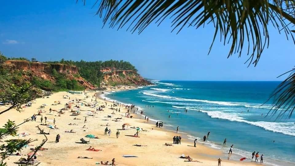 Le coco beach resort varkala cliff في فاركَالا: مجموعة من الناس على شاطئ مع المحيط