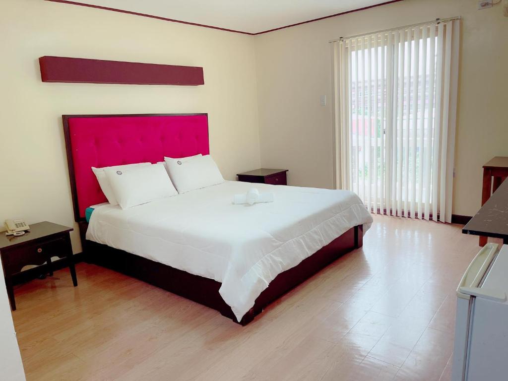 um quarto com uma cama grande e uma cabeceira vermelha em Jun and Helen Hotel and Restaurant em Angeles