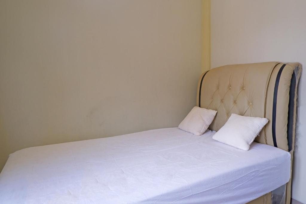 uma pequena cama com duas almofadas brancas em OYO Life 92632 Kost Pondok Kito em Jambi
