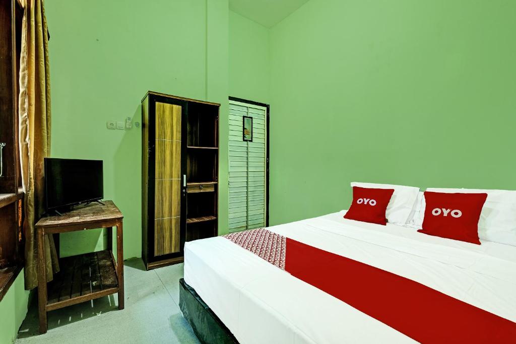 1 dormitorio con 1 cama con almohadas rojas y TV en OYO Life 91682 Homestay Sriti en Kalibanteng-kidul