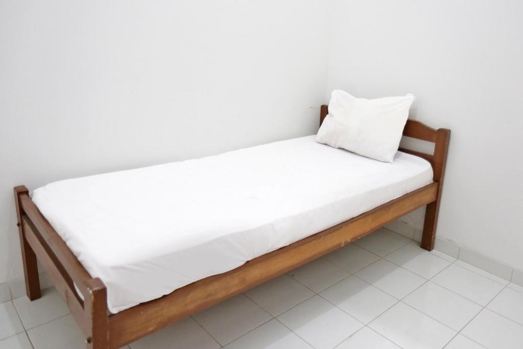 a wooden bed with white sheets and a pillow on it at OYO Life 92925 Kost Bu Mala 2 Syariah in Pasuruan