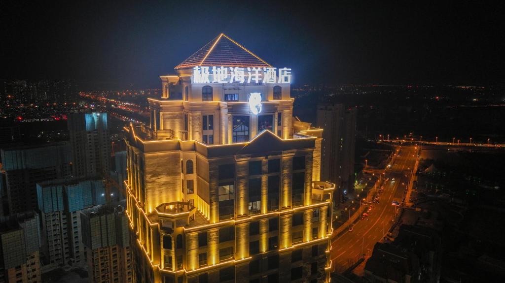 un edificio iluminado con un cartel en él por la noche en Tianjin Polar Ocean Hotel en Binhai