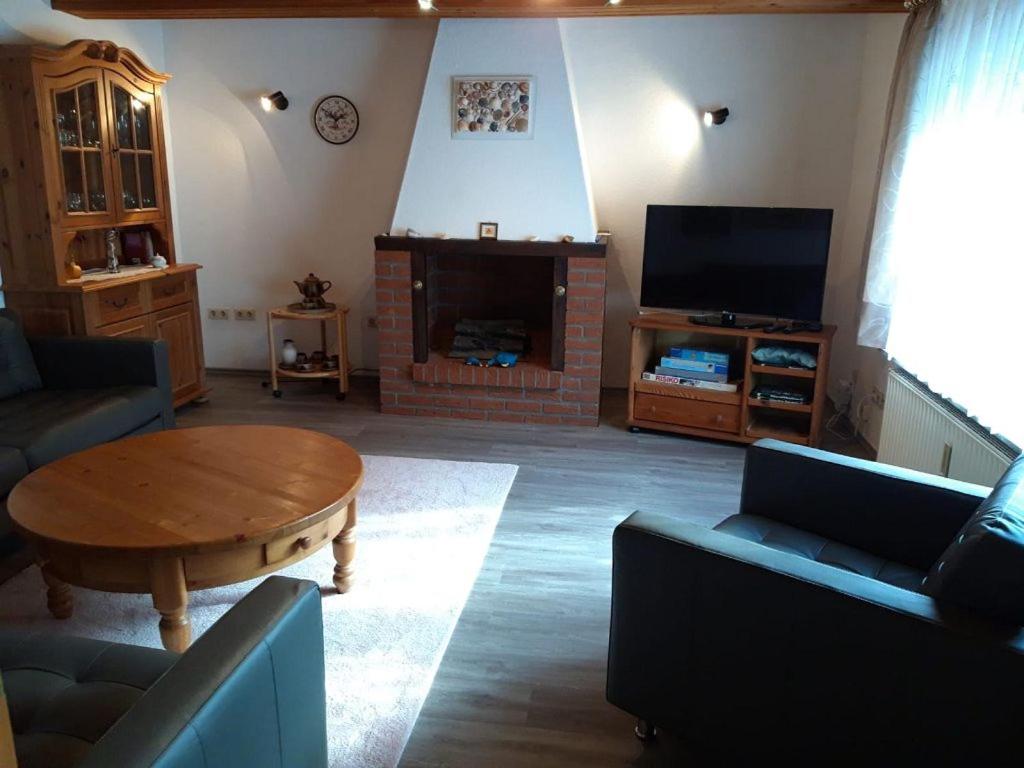 a living room with a table and a fireplace at Haus Marie in Krummhörn