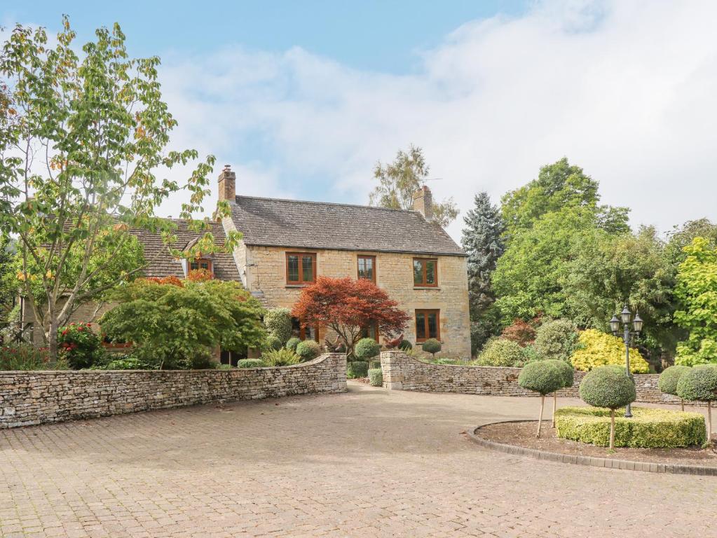 uma casa com uma cerca de pedra e uma entrada de tijolos em Manor Farm em Cheltenham