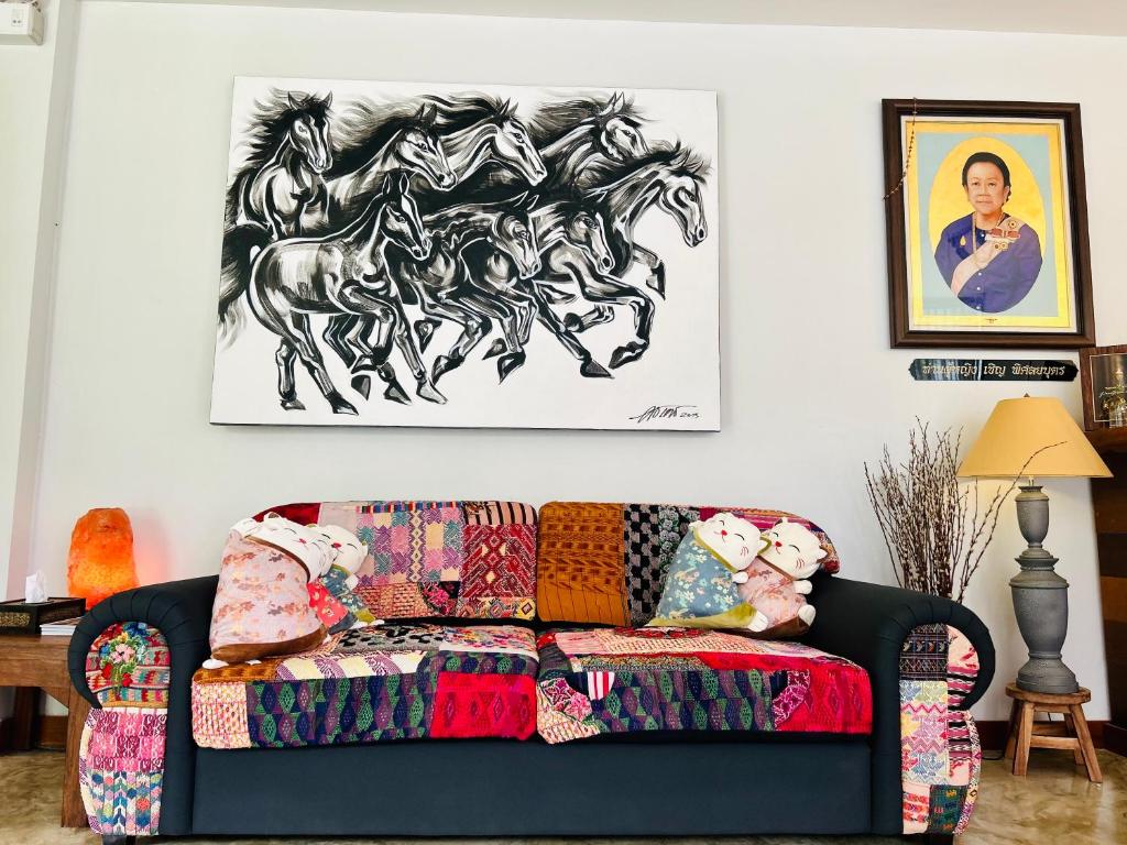 a living room with a couch and a painting of horses on the wall at Chern Chiangmai Boutique Hotel in Chiang Mai
