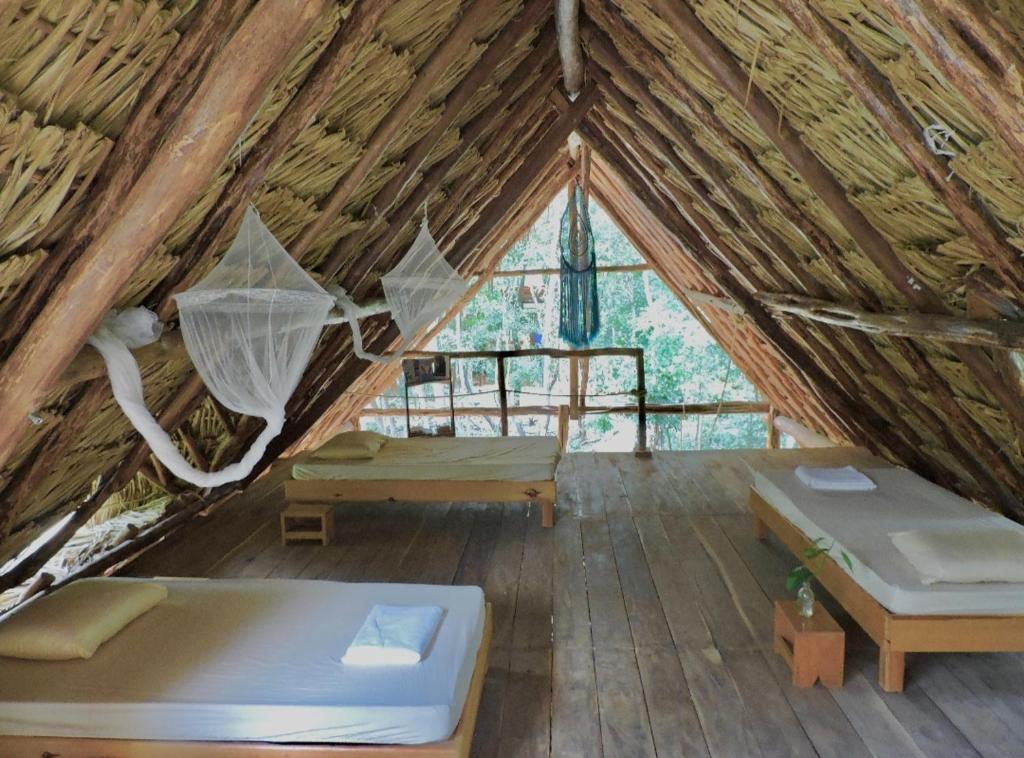 a room with two beds and a hammock in a tent at Rancho Aak in Yaxché