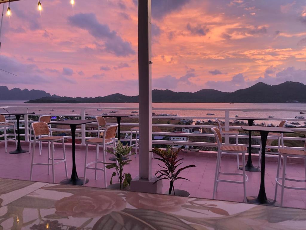 een uitzicht op de oceaan vanuit een restaurant met tafels en stoelen bij Sunburn Suites and Rooftop Bar in Coron