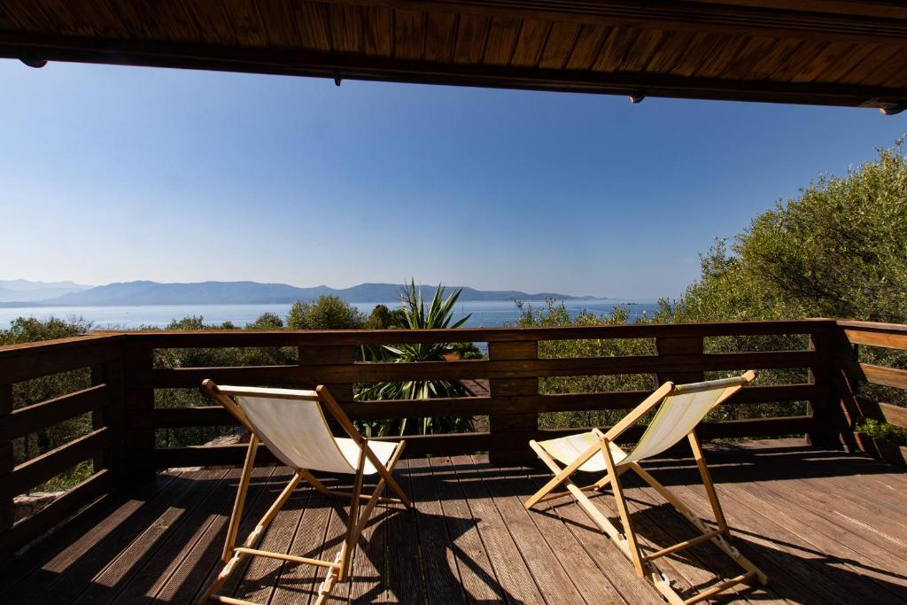 two chairs sitting on a deck with a view of the water at Mare E Monti Chalets in Porto Pollo