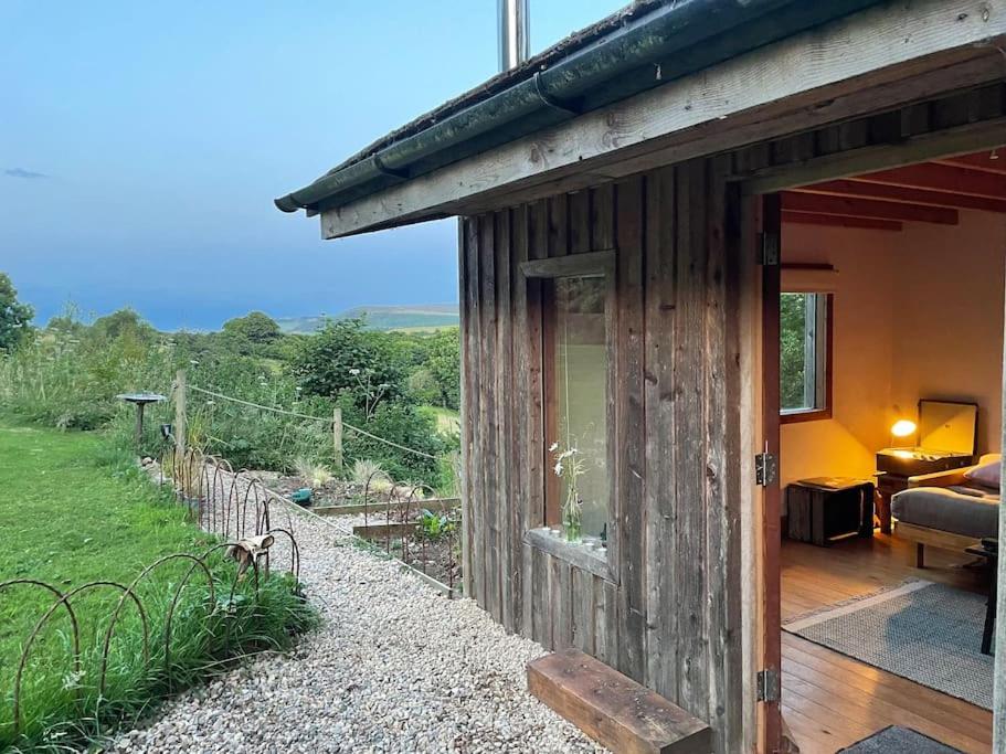 a wooden building with a view of a garden at The Cabin at Shambala- now with sauna available to book! in Whitby