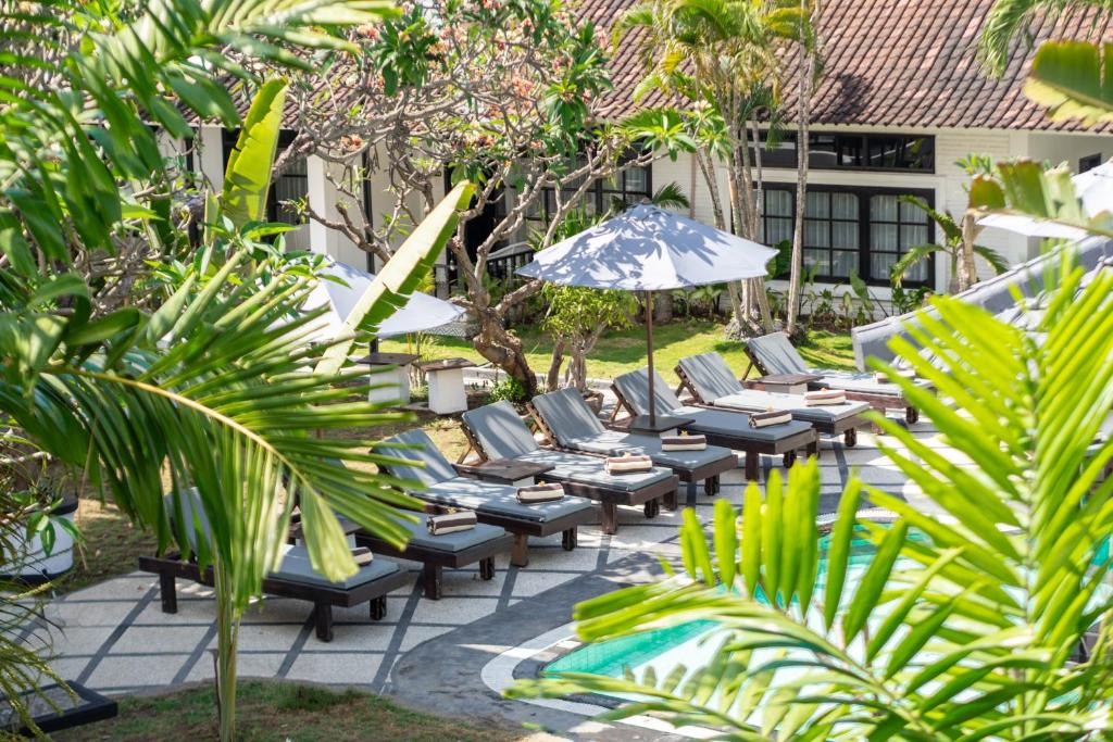 a group of lounge chairs and an umbrella on a patio at Casa Wina Kuta in Kuta