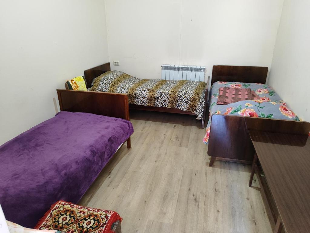 a room with two beds and a wooden floor at Vanand Guest House in Gyumri