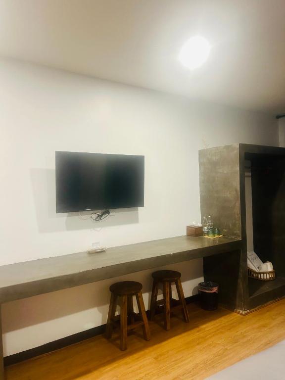 a table with two stools and a television on a wall at Chern Chiangmai Boutique Hotel in Chiang Mai