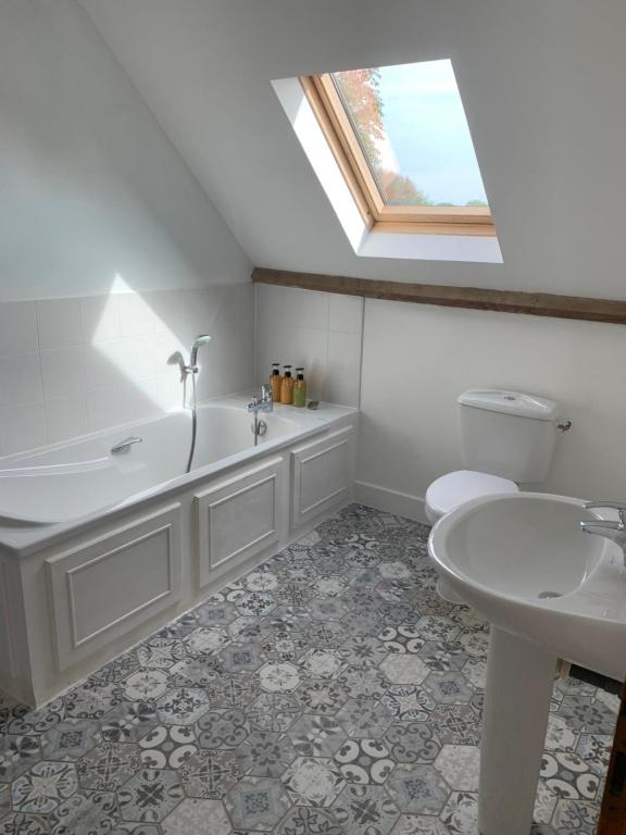 a bathroom with a tub and a toilet and a sink at Les Rouges Terres Gites - La Vieille Grange in Saint-Amand