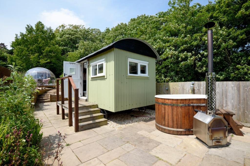 a small green house and a barrel in a yard at Penlea Retreat Luxury Coastal Shepherds Hut 5 Minute Walk to Pubs and Village in Polperro