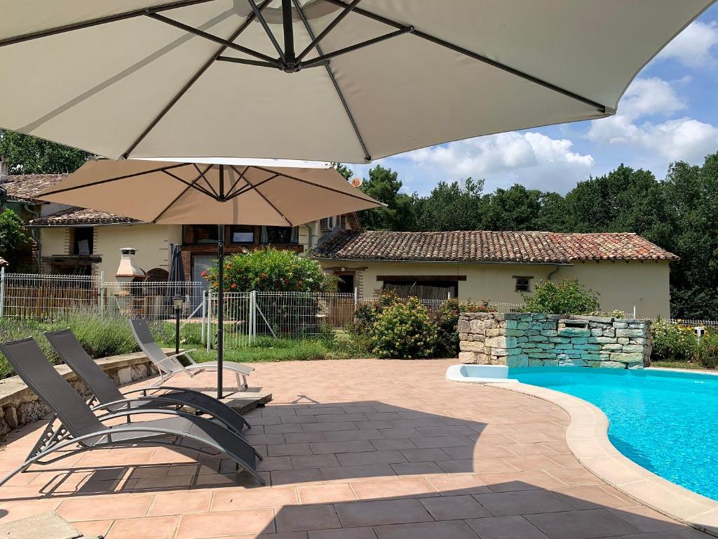 un patio con 2 sillas y una sombrilla junto a la piscina en Gîte Bois et Senteurs, en Lafrançaise