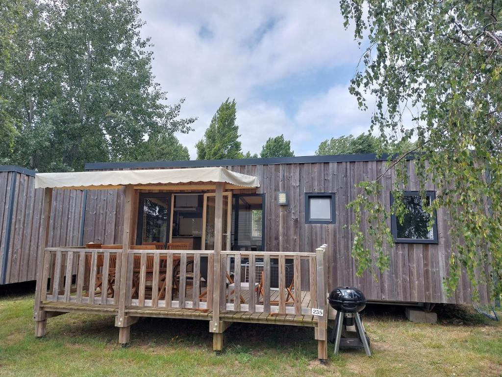 a wooden tiny house with a porch and a grill at Mobil-home La perle bleue in Ouistreham