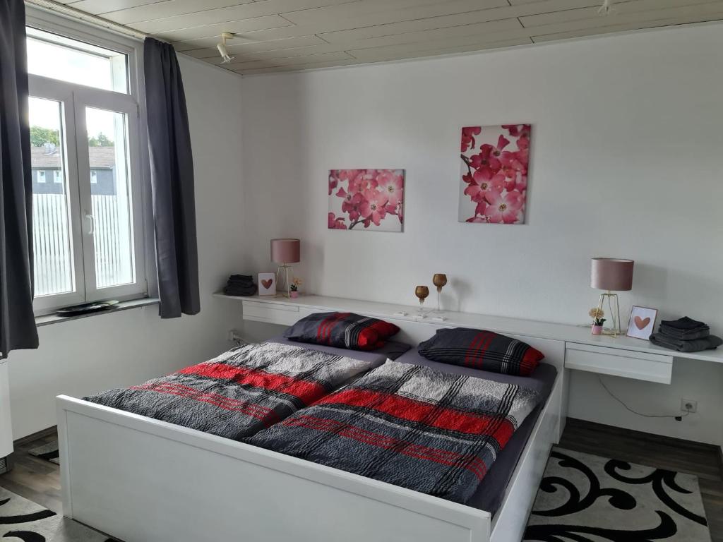 a white bedroom with a bed with a blanket at Drea's Ferienwohnung in Wermelskirchen