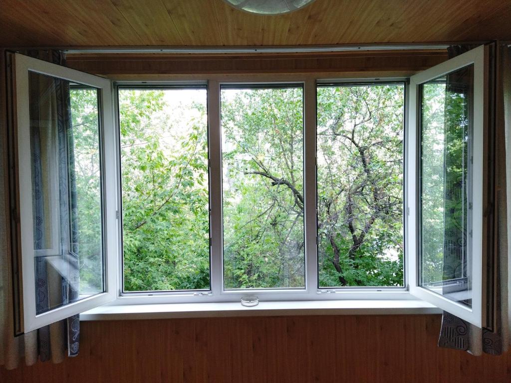 - une fenêtre dans une chambre avec vue sur les arbres dans l'établissement Роза, à Bishkek