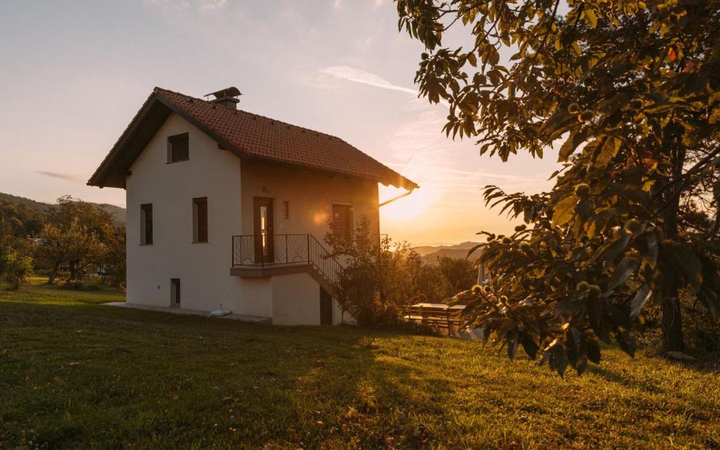 a house on a hill with the sunset in the background at Apartma Hiša na Ravnah in Pišece