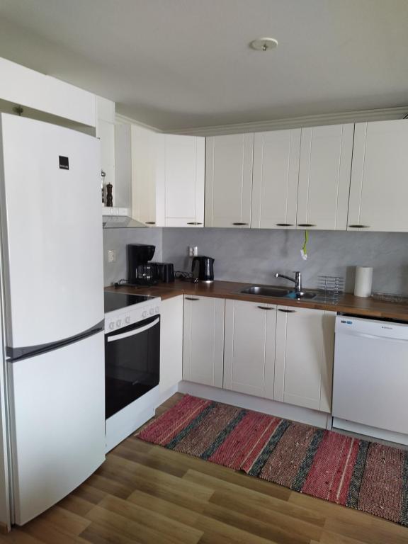 a kitchen with white cabinets and a white refrigerator at Lägenhet Nybrovägen in Lapväärtti