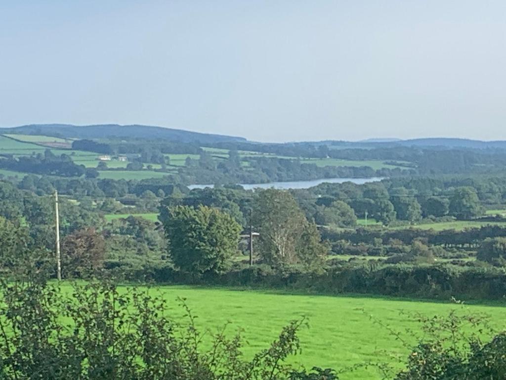 a green field with a river in the distance at Brigadoon lakeview room in Roundwood