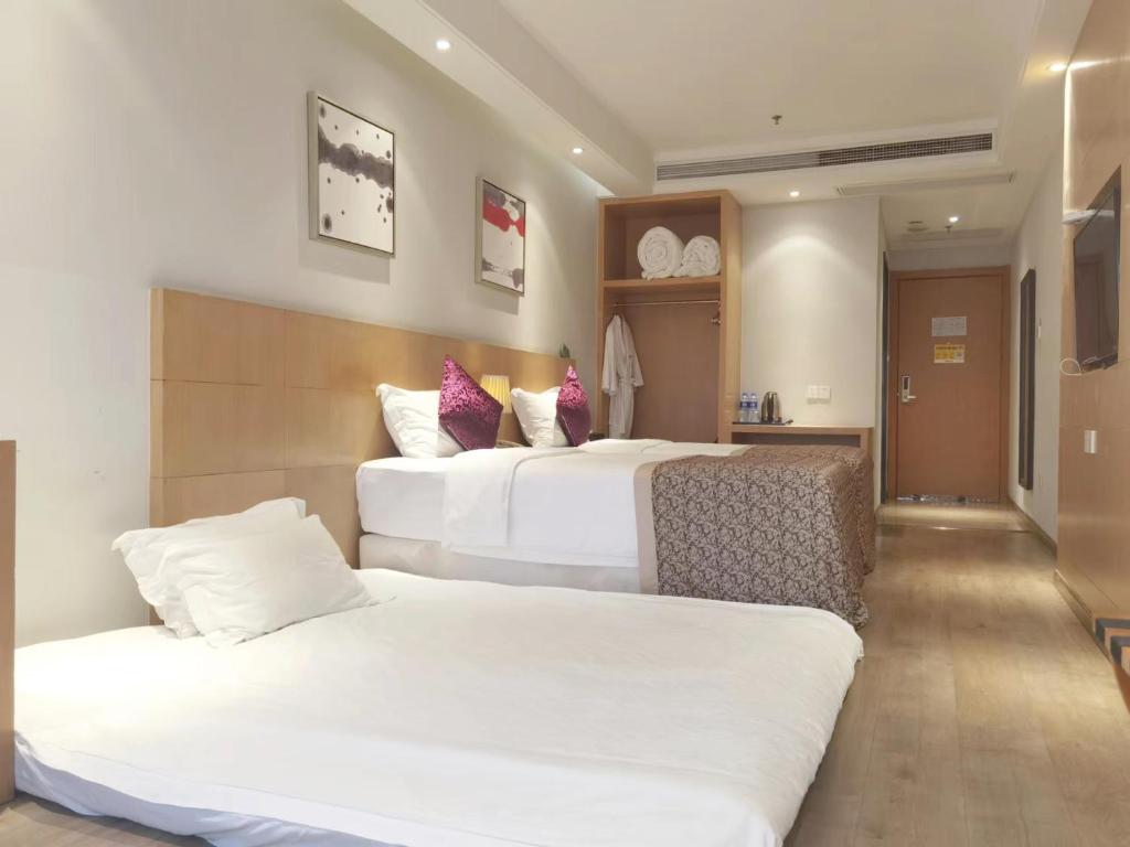 a hotel room with two beds with white sheets at Novo Hotel Chongqing in Chongqing